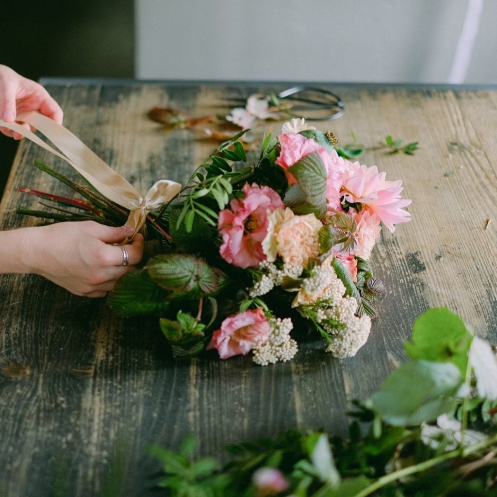 Hands arranging mothers day flower bouquet wooden table