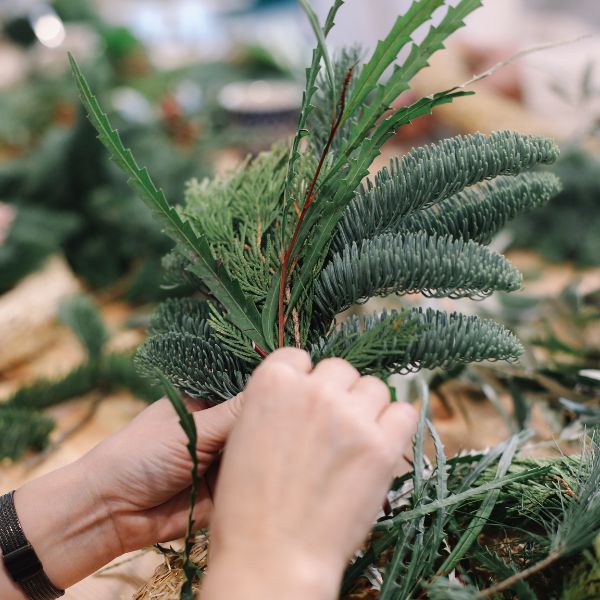 person putting together pine branches and festive greenery for a wreath